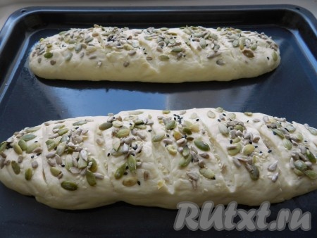 Затем острым ножом сделать неглубокие надрезы на поверхности багетов, смазать водой и посыпать смесью семян. Оставить для подъёма ещё на 10 минут. За это время духовка разогрелась до 220 градусов. Поставить противень с французскими багетами в духовку на 5-7 минут, затем уменьшить температуру до 180 градусов и выпекать ещё 20-30 минут (до готовности).