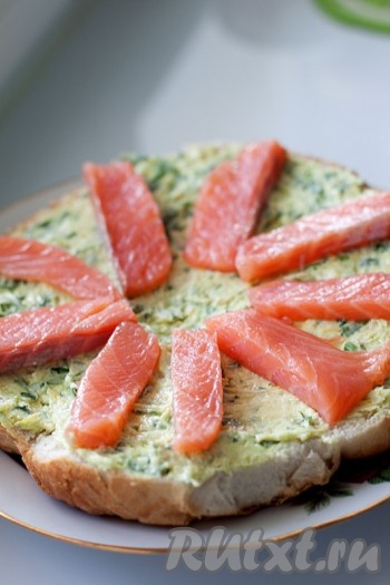 Уложите произвольно на смазанный корж кусочки лосося.