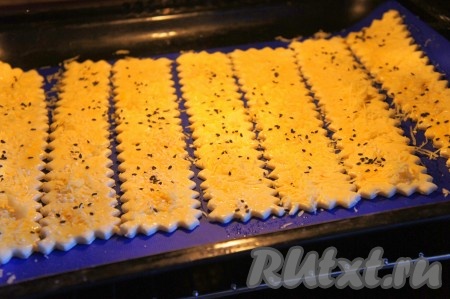 Выпекать сырные палочки из слоеного теста в предварительно разогретой до 200 градусов духовке в течение 20-30 минут до образования устойчивой золотистой корочки.
