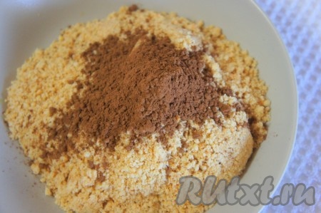 Для приготовления торта можно взять клюкву, уже протёртую с сахаром. А можно протереть специально для этого торта клюкву, для этого нужно свежие ягоды промыть, обсушить (замороженные ягодки следует немного разморозить), затем перемолоть блендером (или с помощью мясорубки), добавить сахар, тщательно перемешать, чтобы кристаллики сахара полностью растворились. Для приготовления торта потребуется 200 грамм клюквы, протёртой с сахаром. Печенье измельчить (довольно удобно выложить печенье в полиэтиленовый пакет, а затем измельчить с помощью скалки), добавить какао-порошок.