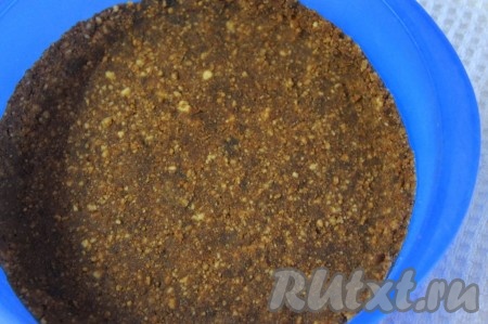 Распределить получившуюся смесь печенья и масла по форме (я использовала силиконовую разъёмную форму диаметром 23 см), плотно прижимая пальцами или воспользовавшись стаканом, формируя небольшие бортики. Это будет основа (корж) нашего торта. Убрать форму с коржом в холодильник на 10-15 минут, чтобы основа охладилась.
