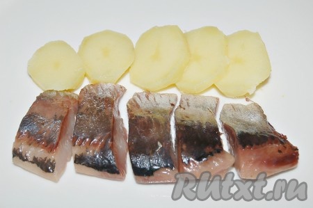 К картошке добавить кусочки очищенной нарезанной сельди. 