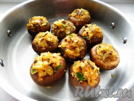 Форму для запекания немного смазать маслом. Нафаршировать шляпки грибов обжаренными овощами так, чтобы получилось с горкой. Духовку разогреть до 190 градусов и запекать фаршированные шампиньоны 20-25 минут, затем посыпать сверху оставшимся сыром и запекать еще 5 минут.
