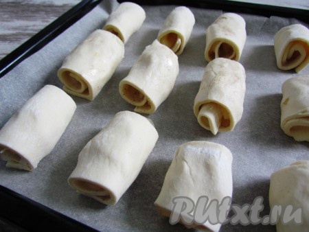 Противень застелить пергаментом, выложить слойки швом вниз. Выпекать примерно 15 минут при температуре 190 градусов. За 5 минут до окончания запекания слойки смазать сладким сиропом, в котором варились яблочные ломтики.
