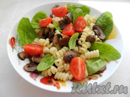 На тарелку с пастой добавить листья шпината, обжаренные шампиньоны и помидоры.