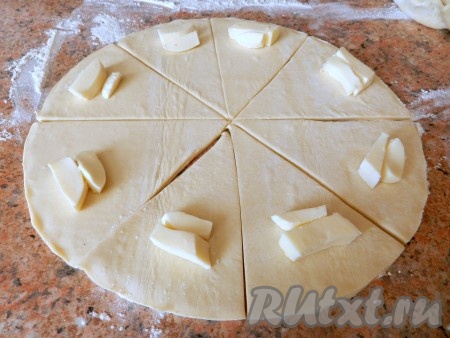 Разделить тесто на 2 части. Каждую часть раскатать, вырезать круг и разрезать его на 8 секторов. На широкий край каждого сектора положить немного сыра и свернуть от краев к центру. 