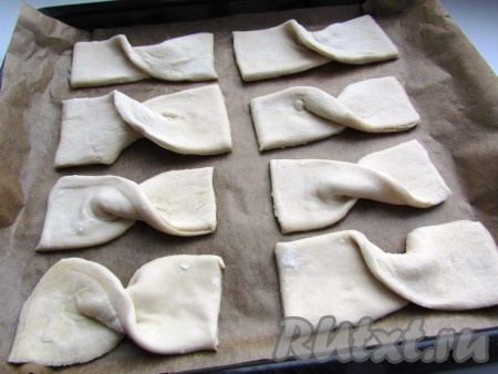 Противень застелить пекарской бумагой. Выложить полоски теста, перегнув каждую посередине.