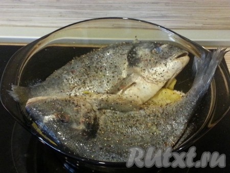 Нарезать лук крупными кольцами (4 штуки), засунуть внутрь рыб, туда же положить по 1 дольке лимона. Выложить нашу дорадо в жаропрочную емкость, полить сверху лимоном. Затем лимон разрезать на несколько долек и подложить под рыбу. Раскидать вокруг чеснок, посолить и поперчить.
