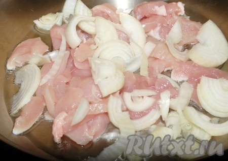 На сковороду налить растительное масло, выложить кусочки курицы и нарезанный репчатый лук.
