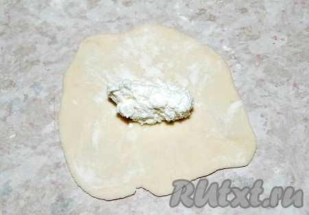 Полученную порцию теста (отрезанный небольшой кусочек теста) раскатать в круг. На середину круга разместить начинку из творога.
