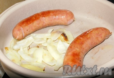 Обжаривать, периодически переворачивая лук и колбаски, до легкого подрумянивания.