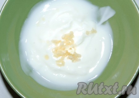 Вылить йогурт в миску, добавить очищенный и пропущенный через пресс чеснок.