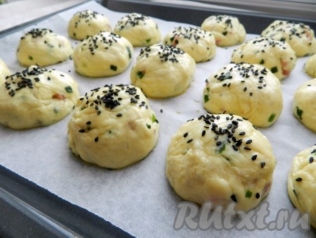 Из готового теста скатать шарики небольшого размера, выложить на противень, застеленный бумагой для выпечки, смазать яйцом, по желанию, посыпать кунжутом и оставить ещё на 30 минут.