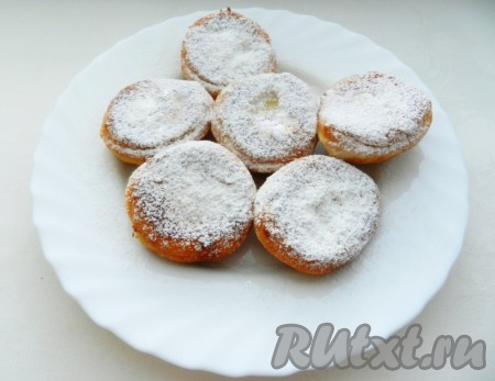 Готовые пышки переложить со сковороды на плоскую тарелку, когда они немного остынут, присыпать их сверху сахарной пудрой. Раскатывая оставшееся тесто и вырезая круглые заготовки, постепенно пожарить все пышки.