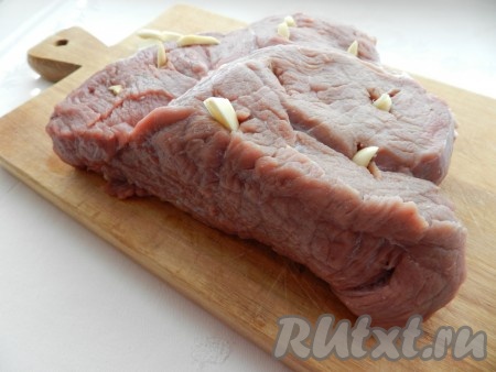 Говядину вымыть, обсушить бумажными полотенцами и нашпиговать чесноком.

