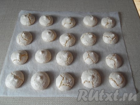 Затем вытащить противень, переложить бумагу для выпечки вместе с безе с противня на негорячую поверхность. Оставить в таком виде кокосовое безе остывать на 15-20 минут.