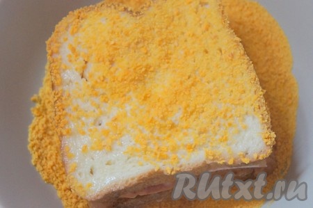 А затем обваливаем бутерброды в панировочных сухарях. Для получения на них более плотной корочки процедуру можно повторить 2-3 раза.