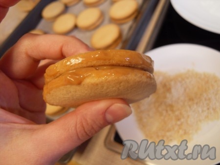 Слегка нанести сгущенку на бока и прокатать печенье, как колесико, по орехам.