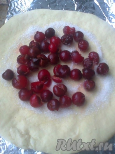 Из вишни удалить косточки. Выложить ее на сахар ровным слоем. Можно взять 400-500 г вишни, тогда ее надо обвалять в смеси 1 столовой ложки муки и 1 столовой ложки крахмала. Отложить первый круг теста вместе с вишней в сторону.