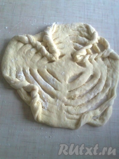 Затем заплести узор - косичку, как в вязании при поднятии петель. Для этого берем самую нижнюю полоску, поднимаем ее (можно перекрутить в виде петли) и загибаем наверх , берем вторую нижнюю полоску, поднимаем ее, продевая в первую самую нижнюю полоску и подтягиваем наверх, получается петля, продеваем в эту петлю третью полоску и так плетем до верха с четырех сторон. Надо слегка растянуть надрезы и при плетении пальцы опускать в муку, чтобы надрезы не слипались. Плести надо на пергаментной бумаге и вместе с ней перенести на начинку.