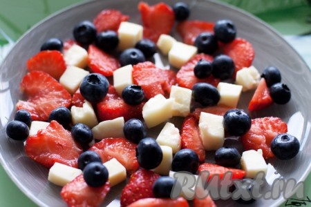 Нарежьте дольками клубнику, квадратиками сыр. Выложите порезанную клубнику, голубику и сыр на тарелку.