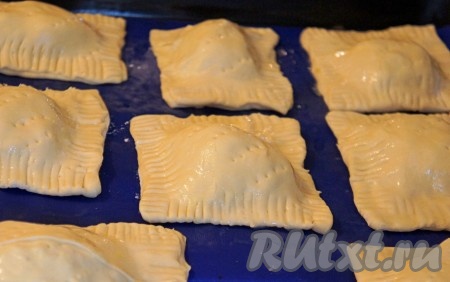 Обмазать слоеные пирожки с капустой взбитым яйцом и сделать несколько проколов вилкой на каждом пирожке. При желании можно их ещё посыпать кунжутом, например (я не посыпала).
