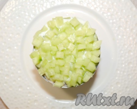 Завершающим слоем салата послужит мелко нарезанный огурец. Сверху тоже смазать.