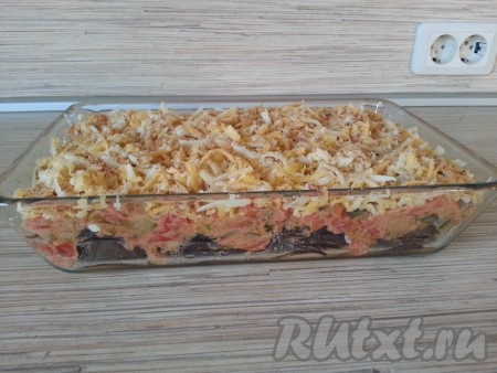 Сверху посыпать овощную запеканку из баклажанов, кабачков и помидоров тертым сыром и затем панировочными сухарями.