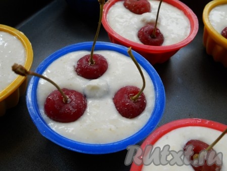 Формочки смазать немного маслом (лучше использовать силиконовые), влить в них тесто и разложить по 2-3 ягоды черешни.&nbsp;