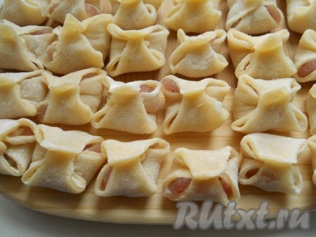 Затем также соединить другие два конца, соединяя посередине. Таким образом налепить все пельмени.
