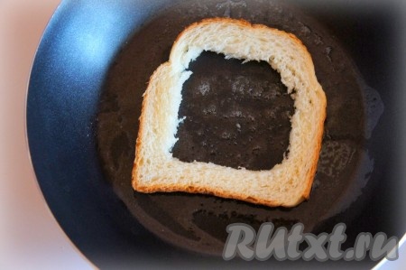 В хлебе вырезать квадратное отверстие (см. фото). Масло разогреть на сковороде, выложить полученную "рамку" из хлеба и обжарить её до румяной корочки с одной стороны, перевернуть и убавить огонь.