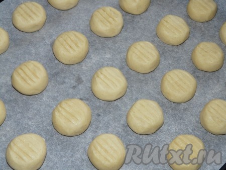 Противень застелить пергаментной бумагой. Сформировать из теста шарики, слегка прижать их сверху ладонью. На поверхности каждой печенюшки, по желанию, сделать вилкой небольшие углубления. Выкладывать печенье нужно на небольшом расстоянии друг от друга, так как печенюшки немного увеличатся в процессе выпечки.