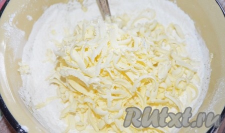 В получившуюся смесь просейте 150 грамм муки, добавьте весь разрыхлитель, перемешайте. Сюда же натрите замороженное масло на крупной тёрке, перемешайте вначале вилкой.