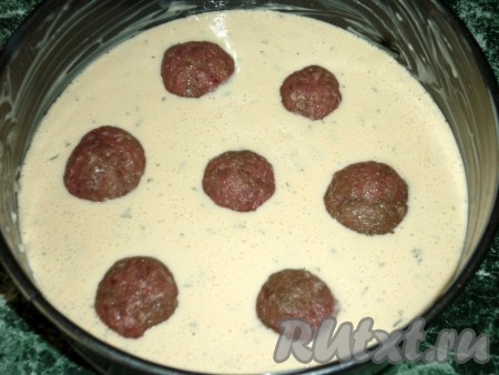 Добавить также просеянную с разрыхлителем муку, перемешать. Тесто должно напоминать сметану средней густоты. Форму для запекания смазать сливочным маслом и вылить туда тесто. Из фарша сделать фрикадельки и выложить сверху на тесто.