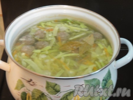 После того как вода с фрикадельками закипит, снять пену, добавить в кастрюлю капусту, картошку, морковь и лавровый лист, дать капустному супу закипеть и уменьшить огонь до минимума.