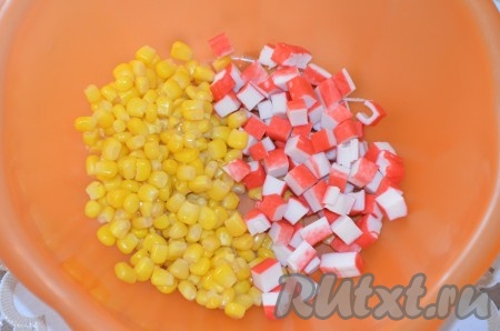 Если крабовые палочки заморожены, их нужно разморозить, затем вынуть из упаковки. С кукурузы слить жидкость. Крабовые палочки нарезать на небольшие кубики и вместе с кукурузой выложить в достаточно глубокую миску.