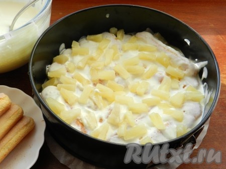 Поверх слоя печенья разложить слой нарезанных ананасов и еще немного крема.