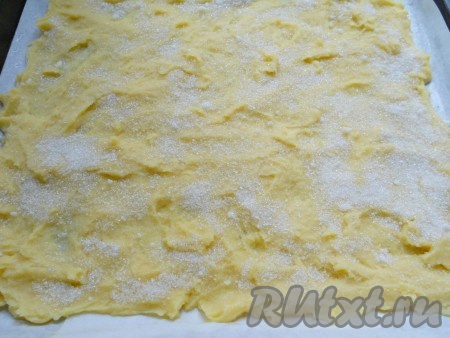 Размазать ложкой или смазанными маслом руками тесто очень тонко (у меня - на весь противень размером 35х32 сантиметра). Сверху лепёшку обильно посыпать сахаром (я корицу не использовала - у меня никто её не любит, если будете готовить с корицей, смешайте её с сахаром).
