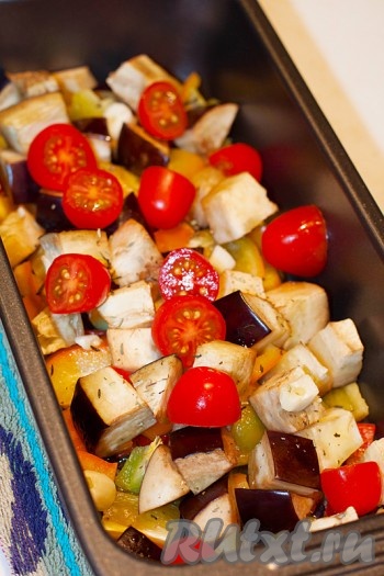 За 5 минут до полного приготовления доложите к овощам разрезанные на две половинки помидоры черри и снова отправьте в духовку. Кусочки курицы в этот момент можно перевернуть на другую сторону, чтобы они зарумянились с обеих сторон. Обычно баклажанам нужно больше времени для полной готовности, так что, по желанию, можно оставить овощи запекаться подольше.
