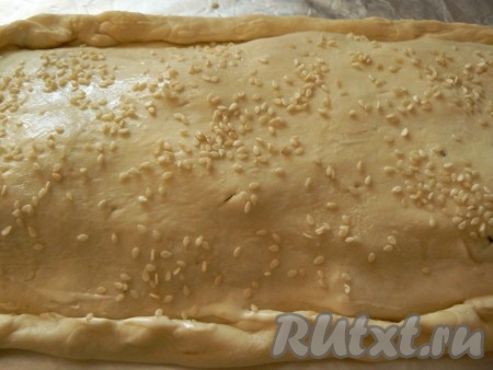 Раскатать второй пласт теста, накрыть им начинку, края защипнуть. Смазать пирог сметаной, посыпать кунжутом, сделать пару дырочек, чтобы выходил пар.&nbsp;
