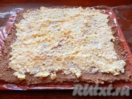 На разделочной доске расстелить пищевую плёнку. Выложить сначала слой паштета, а затем, отступив от краёв паштета, выложить равномерно яично-сырную начинку.