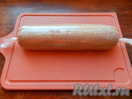 Аккуратно поднимая края плёнки, свернуть печёночный слой с начинкой в рулет. Завернуть плотно получившийся рулет в плёнку, закрутить и завязать концы плёнки. В таком виде убрать рулет из куриной печени с начинкой в холодильник на 2 часа или более.