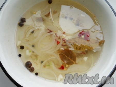 Приготовить маринад для грибов, для этого в небольшую кастрюльку влить 500 миллилитров воды, добавить соль, сахар, очищенный лук, нарезанный тонкими полукольцами, перец горошком, душистый перец, очищенный и нарезанный чеснок, лавровый лист, всыпать кориандр. Поставить на огонь, довести до кипения, варить на небольшом огне 1 минуту. Убрать с огня, дать маринаду немного остыть и влить уксус, растительное масло, добавить мелко нарезанный перец чили.