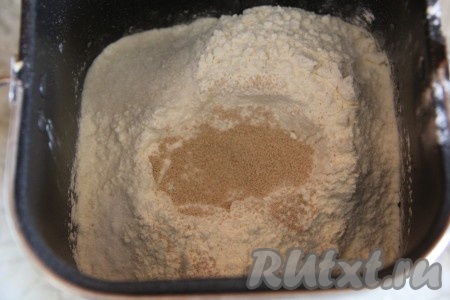 Сверху разместить муку, поместить соль и сахар в разные углы ведерка. Дрожжи всыпать в углубление в центре муки.
