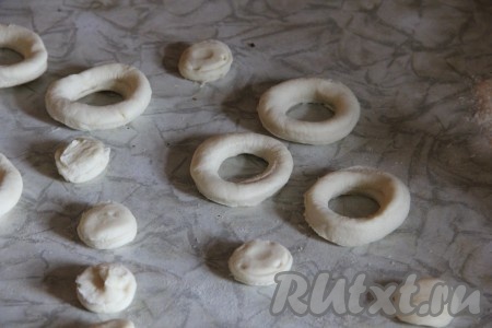 Из второй части теста выдавить круги той же рюмочкой (или специальной формой). Формой меньшего размера (например, крышкой от пластиковой бутылки или рюмочкой) в середине получившихся кружков выдавить круг меньшего диаметра. Получатся "бублики" из теста.
