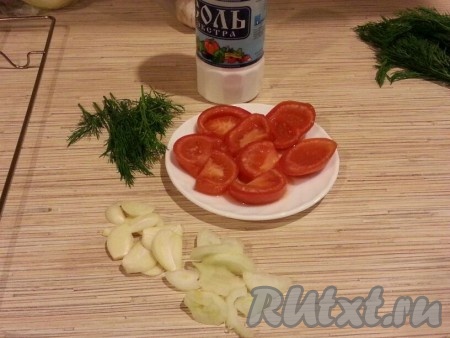 Солим и натираем специями рыбу внутри и снаружи. Лук чистим. Нарезаем лук и помидоры на полукружочки. Мелко нарезаем укроп. Очищенные зубчики чеснока нарезаем на пластинки.