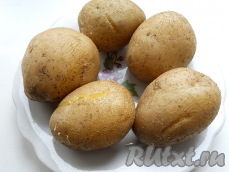 Картофель хорошо вымыть, выложить, не очищая от кожуры, в кастрюлю, полностью залить водой. Поставить кастрюлю на огонь, отварить картошины до готовности (на отваривание потребуется минут 25, картофель должен легко прокалываться вилкой, но при этом должен сохранять форму). Выложить варёную картошку на тарелку, остудить.