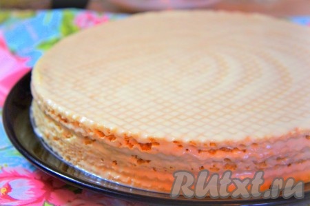 Тёплым кремом смазываем каждый вафельный корж с двух сторон, убираем излишки крема и укладываем коржи один на другой, плотно прижимая их друг к другу.
