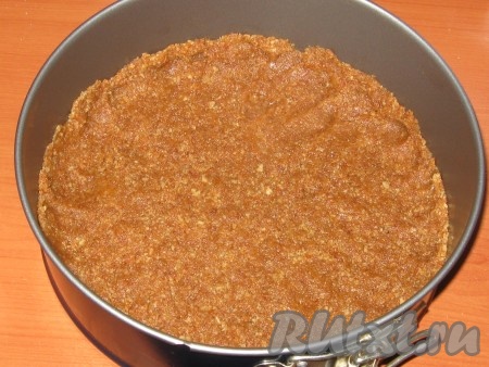  Масляную крошку утрамбовать по дну формы (у меня разъёмная форма диаметром 22 сантиметра), сделать бортики высотой, примерно, 0,5 сантиметра.