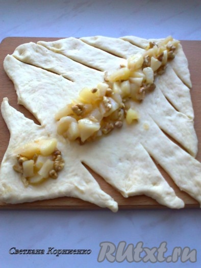 Разворачиваем тесто и надрезаем бока полосками до линии наметки. Выкладываем начинку из яблок,
